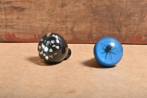 GEAR SHIFT KNOBS: Two gear shift knobs including a blue knob with spider, and a black knob with coloured stone inside