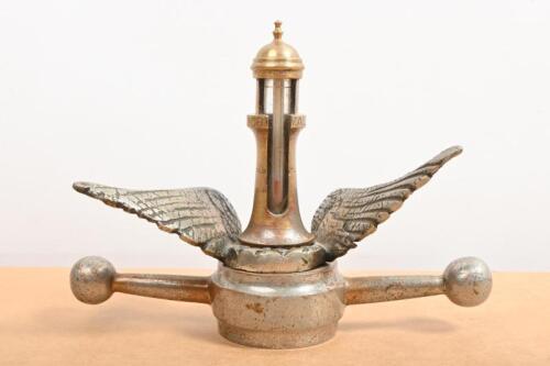 MOTOMETER: A decorative mascot combination including dog bone with wings, surmounted by a brass lighthouse thermometer