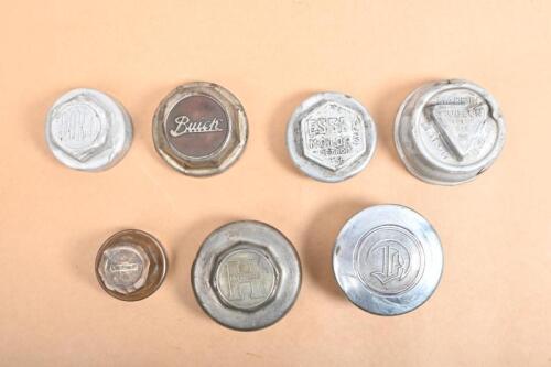 GREASE CAPS: A collection of seven grease caps including Hudson, Hupmobile, Essex, Buick, Dort, Chevrolet and one other