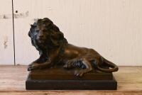 AFTER BARYE: A cast bronze figure of a recumbent lion on black marble base after the original model by Antoine-Louis Barye (French, 1795-1875), 20.5cm high