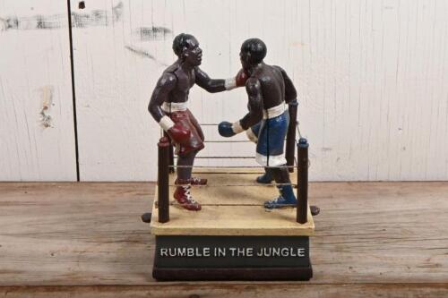MUHAMMAD ALI: A cast iron moneybox commemorating the Rumble in the Jungle between Muhammad Ali and George Foreman, 1974, with mechanical operated arms, 21cm high