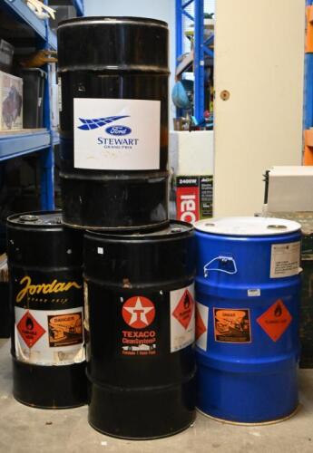 DRUMS: Three fifty litre black oil drums, one with "Jordan Grand Prix sticker, one with Texaco sticker and one with Ford Stewart Grand Prix sticker, together with another fifty litre drum