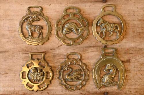 HORSE BRASSES: A collection of six horse brasses with ornate designs featuring animals such as fish, swans and horses.