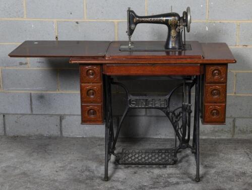 SINGER: An Edwardian Swinger sewing machine table, the table oak on cast iron base and workings, appears to be in working condition, serial number D1339661 indicating 1909, 77cm high, 93cm wide, 46cm deep