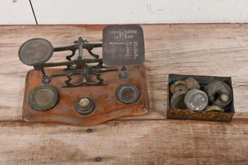 POSTAGE SCALES: An antique brass 'POSTAL RATES FOR LETTERS' countertop postage scales, with embossed rates, graduated brass weights, mounted on timber base
