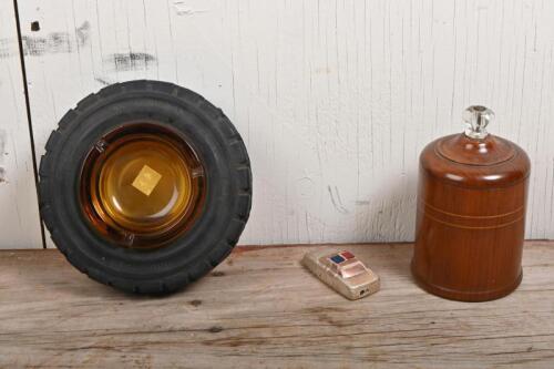 SMOKING: Three vintage novelty smoking related items, comprising a tractor tyre form ashtray, a police car lighter complete with siren upon opening, and a turned wood cigarette dispenser, the dispenser 15cm high
