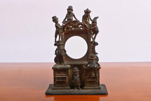 CLOCK MOUNT: A Victorian novelty metal clock housing. Measurements of 17.5cm high, 12.5cm wide & 6.5cm deep; clock mounting diameter of 5.5cm