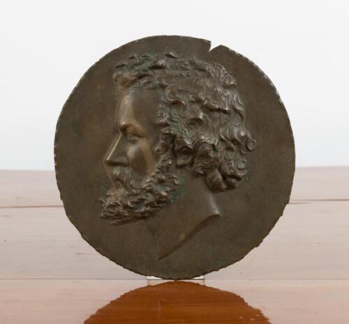 GREEK BRONZE: A bronze plaque featuring an image of a mans head. Plaque with diameter of 21cm