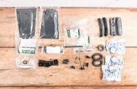 E -TYPE: A collection of Jaguar E-Type V12 new old stock items. Shift ID plate (2), brush for ID plate, two door recess panels, rubber bumper overriders, carburettor dampers, rear hinge escheons,'DEFROST' label bracket & others