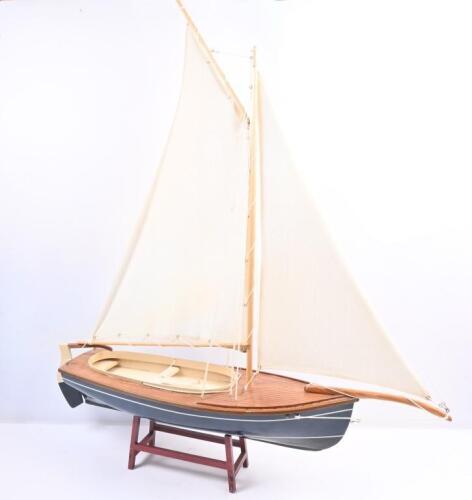 YACHT: A wooden sailing yacht model with fabric sails, complete with stand. approx 80cm long, 98cm tall.