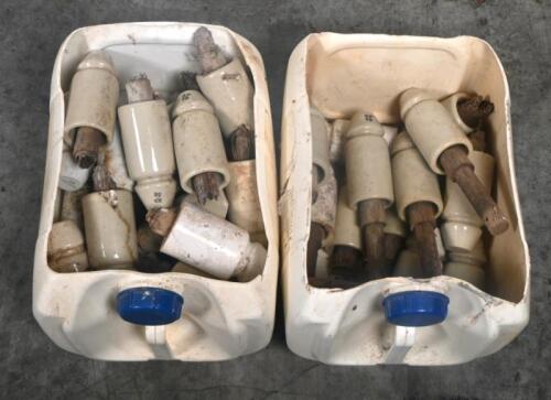 INSULATORS: A large selection of ceramic telephone wire insulators, mostly affixed to wooden posts.