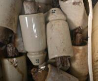 INSULATORS: A large selection of ceramic telephone wire insulators, mostly affixed to wooden posts. - 2