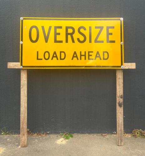 OVERSIZE LOAD: A large 'Oversize Load Ahead' metal sign mounted to timber stand along with flag set and banner