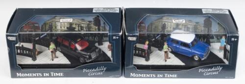 354 · MOTORMAX MOMENTS IN TIME: Set of 2 1:64 scale Motormax Moments in Time Series Dioramas, both set on a corner of London's Piccadilly Circus, 1 featuring a typical London Black Cab, and 1 featuring a Blue and White vintage Mini, both clear display boxed.