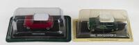 ALTAYA MINIS: Set of 2 1:43 scale Altaya Mini Coopers, 1 Green and White BMC Mini Cooper S, and 1 Red and White Mini Cooper, both on labelled plinths in clear blister packs.