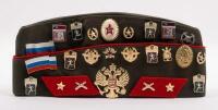 USSR: A Soviet Military styled Garrison hat, green with red piping. Fitted with various Soviet era pins.