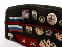 USSR: A Soviet Military styled Garrison hat, green with red piping. Fitted with various Soviet era pins. - 3