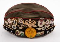 USSR: A Soviet Military styled Garrison hat, green with red piping. Fitted with various Soviet era pins and three patches attached.