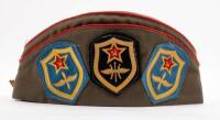 USSR: A Soviet Military styled Garrison hat, green with red piping. Fitted with various Soviet era pins and three patches attached. - 5