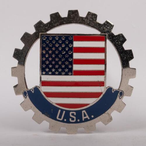 USA: MEXICO: A USA grille badge, cog design with painted centre, mounting pins, 8cm in diameter