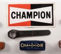 DISPLAY BOARD: A display board consisting of a Champion spark plug sticker, several spark plugs and early tin spark plug containers plus one wrench, 21cm high, 48cm wide - 4