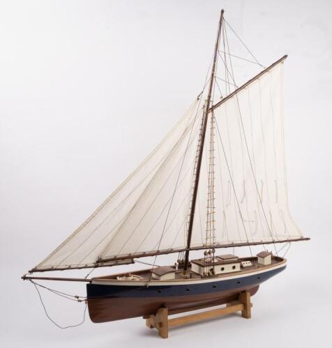 YACHT: A wooden model of an early sailing yacht with large fabric sails, approximately 84cm in length, 83cm high, comes with a stand for base