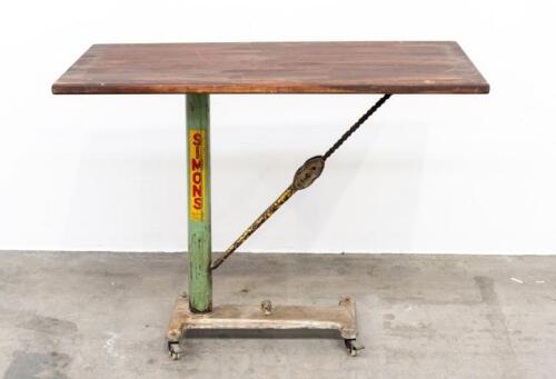68A · BED TABLE: An industrial style work/bed table on a cast iron base, featuring pipe wrench and chain support, mounted to small castor wheels, 93cm high, 120cm wide