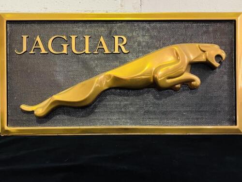 JAGUAR: A framed 'leaper' made of gold plastic mounted on a black background, 75cm wide x 38cm high [Location: Sydney]