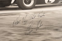DENIS HULME: A large original black & white photograph by Lawrence Thomas of Dennis Hulme racing a BT19, signed by Dennis Hulme 'With Very Best Wishes - Dennis Hulme', 49cm high, 59cm wide - 2