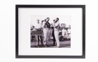 JACK BRABHAM: A photograph signed by Jack Brabham, features Jack Brabham being presented a winners wreath by Stirling Moss, framed & glazed, image 20cm high, 24cm wide