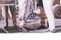 JACK BRABHAM: A photograph signed by Jack Brabham, features Jack Brabham being presented a winners wreath by Stirling Moss, framed & glazed, image 20cm high, 24cm wide - 2