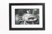 JACK BRABHAM: A B/W photograph featuring Sir Jack standing over a Brabham racing car, signed in black marker Jack Brabham & Ron Tauranac