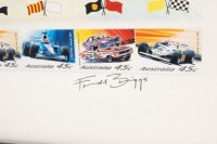 STAMP SET: A signed 12 stamp set depicting well known Australian Racing cars, one featuring a Repco-Brabham at Sandown 1966, mounted, framed & glazed, set 8cm high, 18.5cm wide - 2