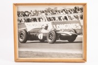 T53: A B/W photograph featuring Jack Brabham in his works Cooper T53 at speed, framed 32cm high, 39.5cm wide overall
