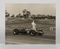 COURAGE: A 1968 period black and white photograph of Piers Courage racing at Sandown Raceway, Victoria. Signed by Piers Courage. Measures 38cm wide, 30.5 cm high