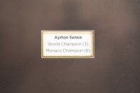 SENNA: A framed collage containing a print after the original airbrush painting by G.Willem Lubach titled 'Ayrton Senna - JPS Lotus 98T "86" along with Ayrton Senna signature on card mounted within frame. Measures 38.5cm high, 62.5cm wide - 3