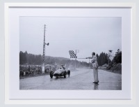 ALBERTO ASCARI: A large and impressive photograph by Klemantaski of Alberto Ascari crossing the finish line to win the 1952 Belgium GP at Spa, image 58cm high, 82cm wide, mounted framed and glazed, overall 82.5cm high, 106cm wide [Location: Melbourne]