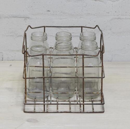 A wire 9 bottle freight rack, with 6 bottles including 5 quart and 1 x one litre oil bottles. 32.5 wide x 20cm high.