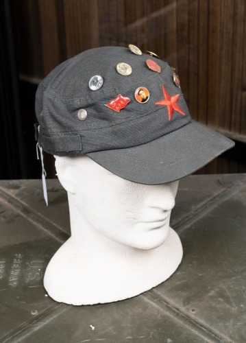 CHINESE CAP: A Chinese communists cap, adorned with badges of Chairman Mao