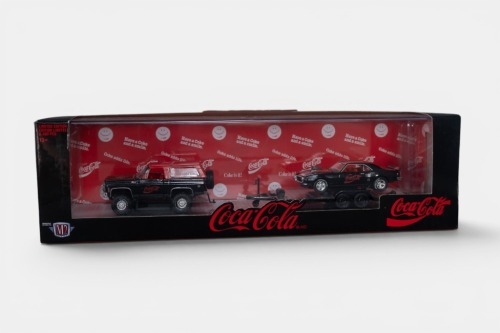 CHEVROLET: A 1:64 scale M2 hauler set of models, consisting of a 1973 Chevrolet K5 Blazer with a 1968 Pontiac Firebird on a trailer, all wearing the iconic Coca-Cola livery, model number TW18, limited edition 8400 pieces