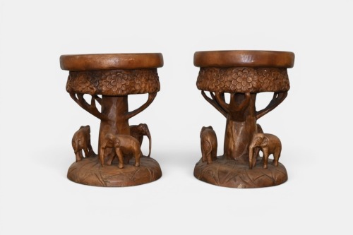 SIDE TABLES: Two solid timber carved side tables/stools featuring elephants, 48cm high, 39cm diameter