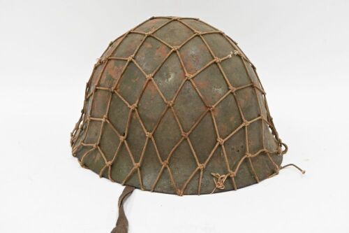 HELMET: A vintage military helmet, with interior leather strapping and exterior webbing