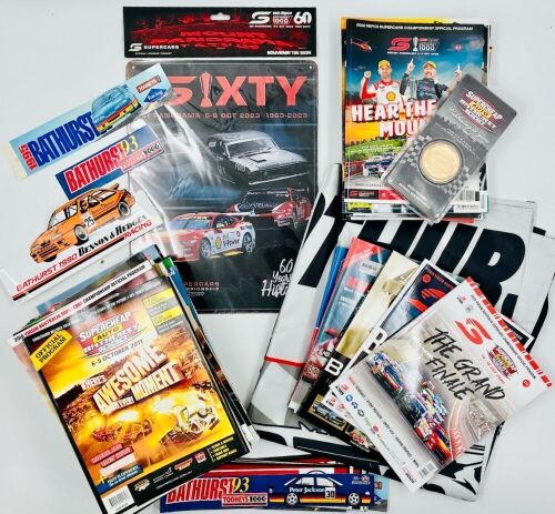BATHURST: A large group of Bathurst memorabilia including a flag from the 2024 race, a commemorative coin celebrating 50 years of the Bathurst 1000. a 60th anniversary tin sign and a group of race programmes and stickers [Location: Sydney]