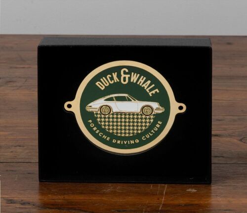 34 · PORSCHE: An unused enamel grill badge by Duck & Whale, Porsche Driving Culture, boxed with bolts