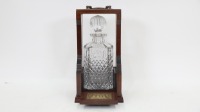 TANTALUS: A cut crystal decanter in timber tantalus, 30cm high