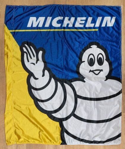 49 · MICHELIN: A circa 2000's Michelin flag featuring a waving Bibendum, appears unused, 135cm high, 135cm 113cm wide