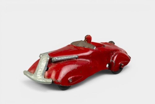 PUSH CAR: A circa 1930s tinplate push car with driver toy, 15cm long