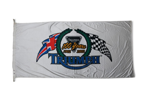 TRIUMPH: A large commemorative Triumph flag '100 Years of Triumph 1902-2002', 85cm high, 185cm wide [Location: Melbourne]