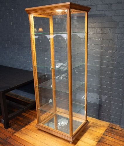 DISPLAY CASE: A tall display case, has timber frame, glass walls, four glass shelves, lockable door, on castors, 188cm high, 65cm wide, 49cm deep