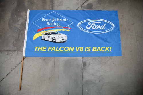 SETON: A Circa 1993 Ford, Peter Jackson Racing 'The Falcon V8 Is Back!' fabric flag on pole signed by Glenn Seton, measures 100cm high, 117.5cm wide overall